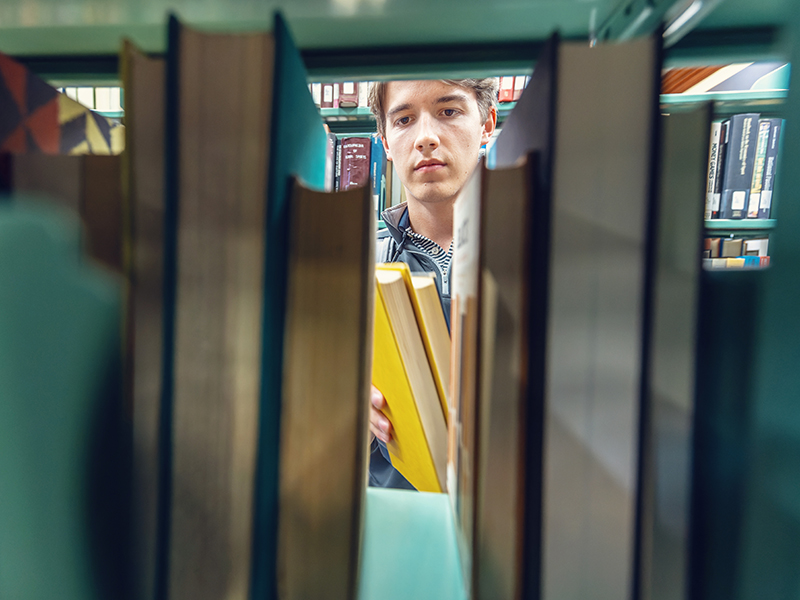 a student looking though a stack of books