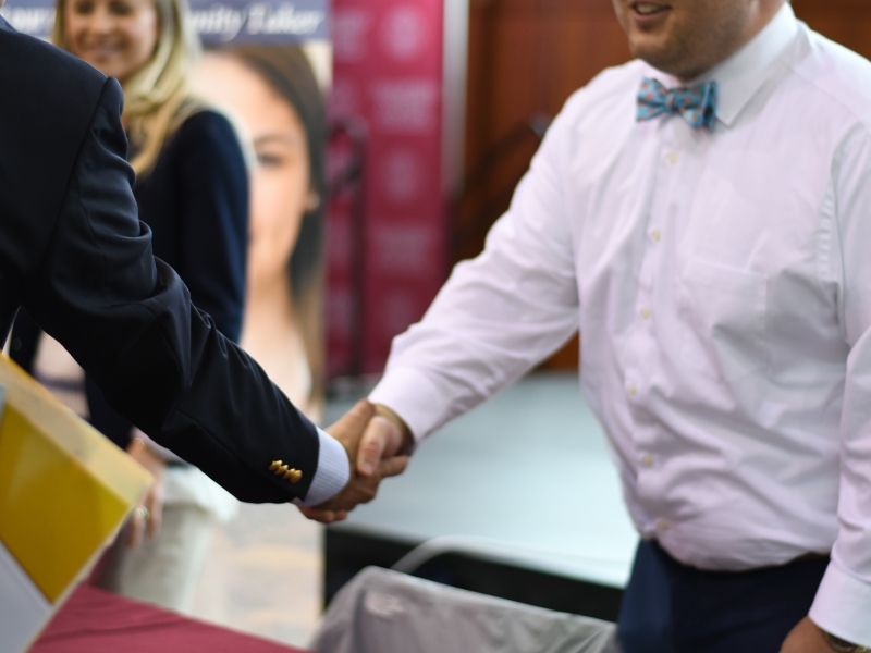 a close-up image of men shaking hands at a career fair