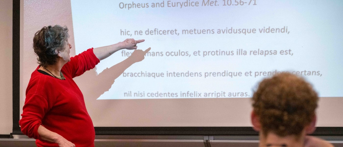 Professor of Classics reading Latin at the white board in class