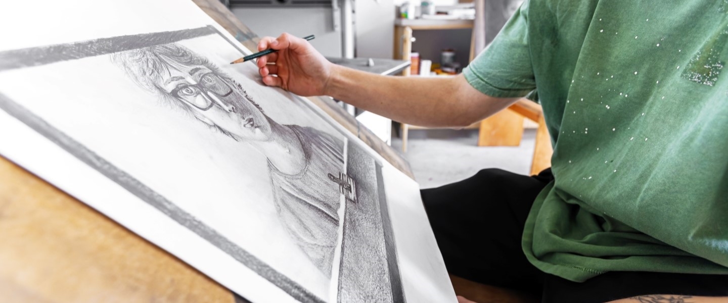 a student's hand drawing a portrait