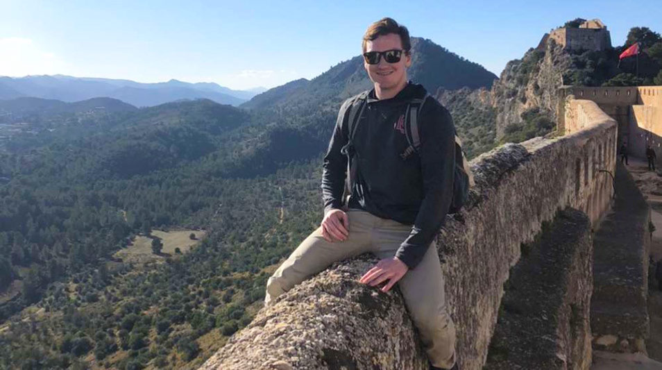 a student sitting on a mountain top wall in Spain
