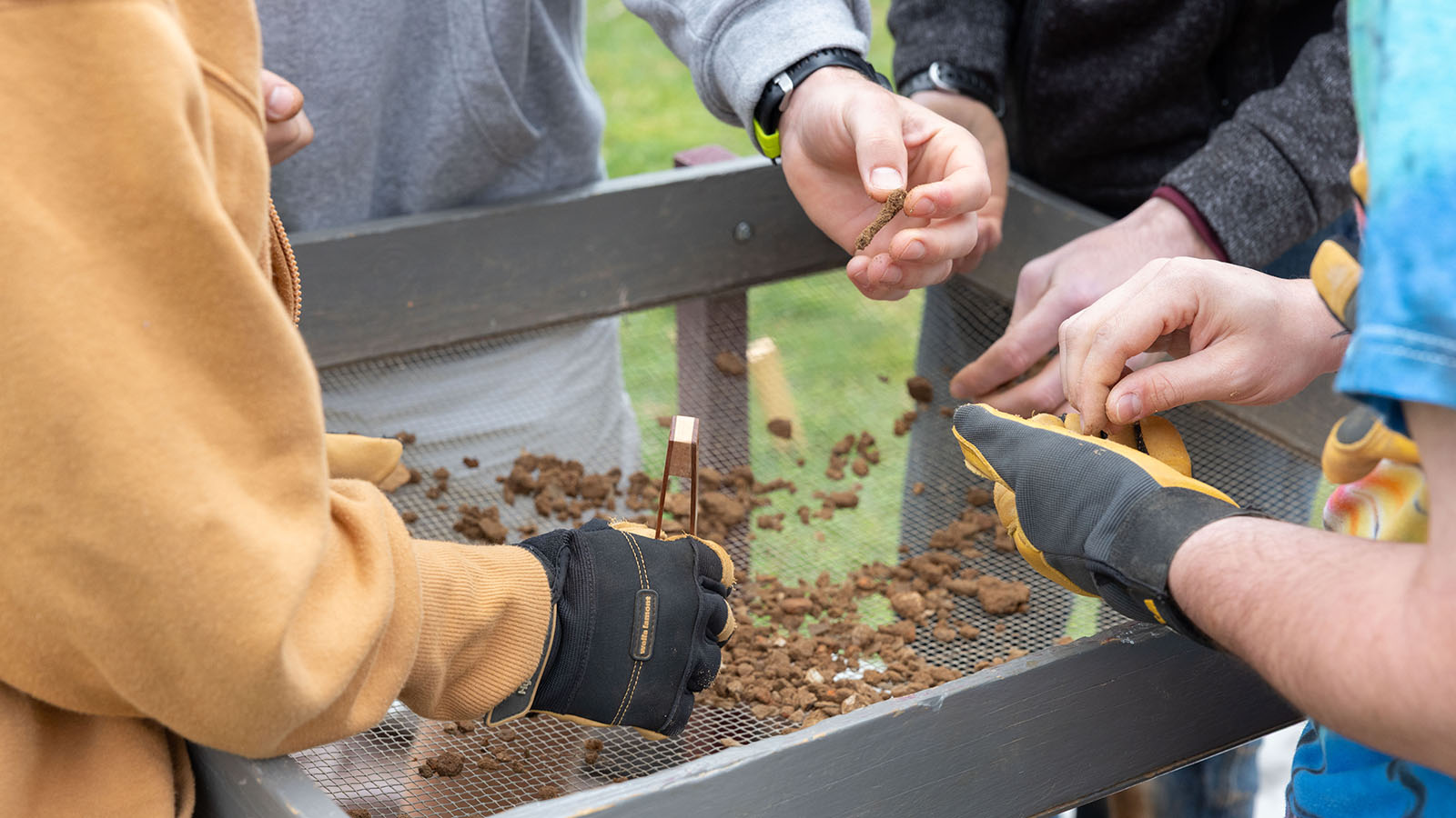 students handling pebbles at an archaeology site