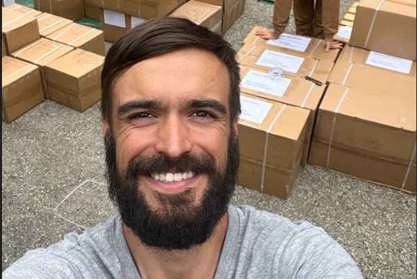 Yevhen (Zhenya) Goncharov posing in front of stack of Amazon.com boxes