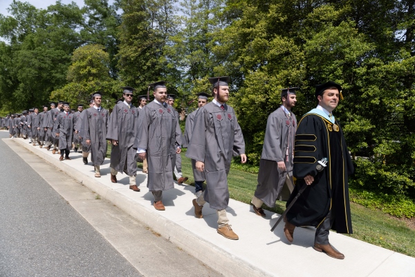 Dean Pantele processing with students in regalia
