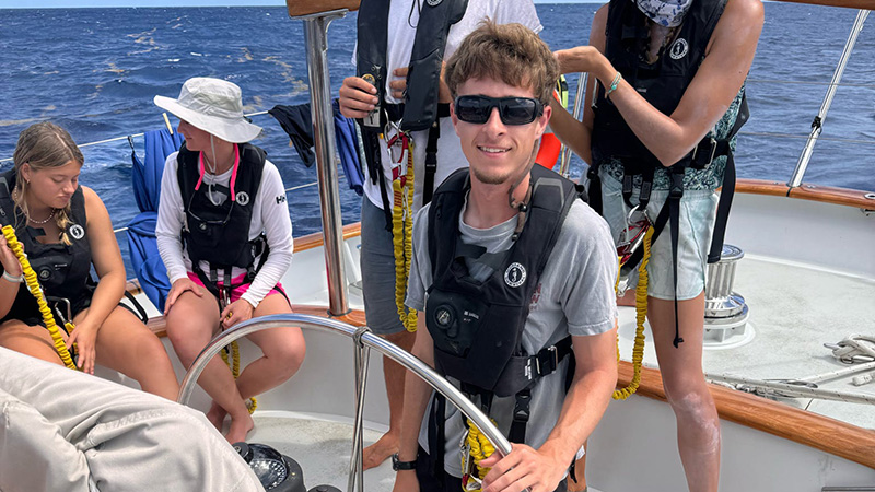 Watson Grabar at the helm of a sailboat