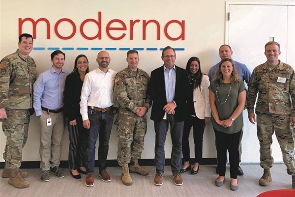 Scott Nickerson '95 standing with colleagues in front of a Moderna sign
