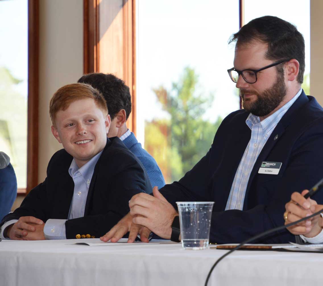 Logan Pryor sitting on an alumni panel behind a table