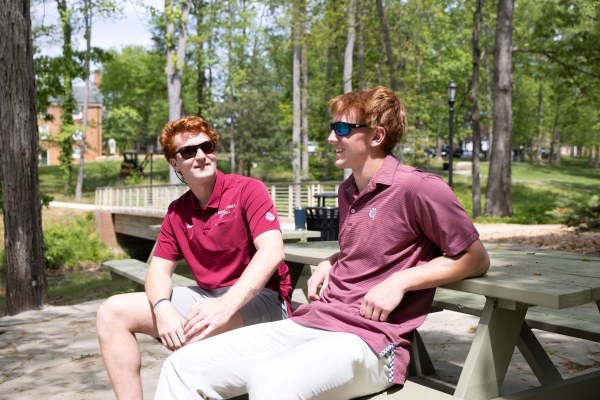 Lasso brothers sitting outside at a picnic table talking