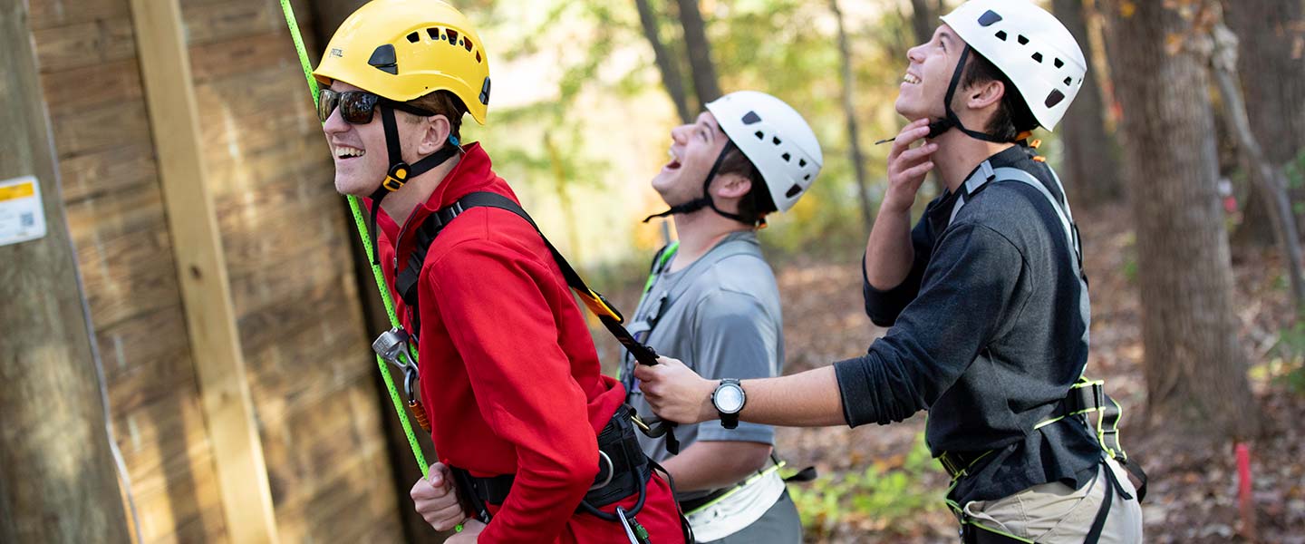 students in helmets at the base of a climbing wall