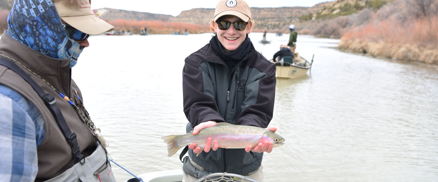 a student showing his trout while on a fly fishing trip