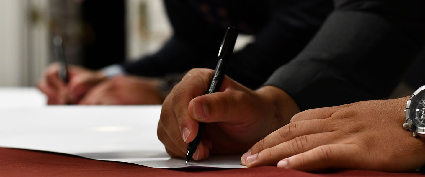 Hands filling out and signing forms for Hampden-Sydney College